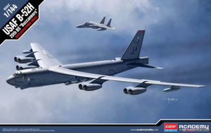 A scale model of the B-52H Stratofortress aircraft, depicted in gray camouflage paint, with visible engines and wing structure against a cloudy sky backdrop.